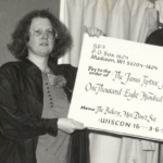 (left to right) Diane Martin and Jeanne Gomoll holding a check for $1000, raised through sales of the cookbook, The Bakery Men Don’t See