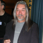 M. John Harrison wearing tiara and holding fabric cake containing chocolate