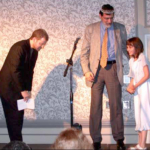 John Kessel encourages his daughter to transfer the tiara from the previous winner (Kessel) to the 2003 winner, Matt Ruff, who then bows to receive this honor. Photo by Michael Ward