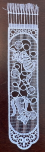 White lace bookmark depicting cats playing with yarn.
